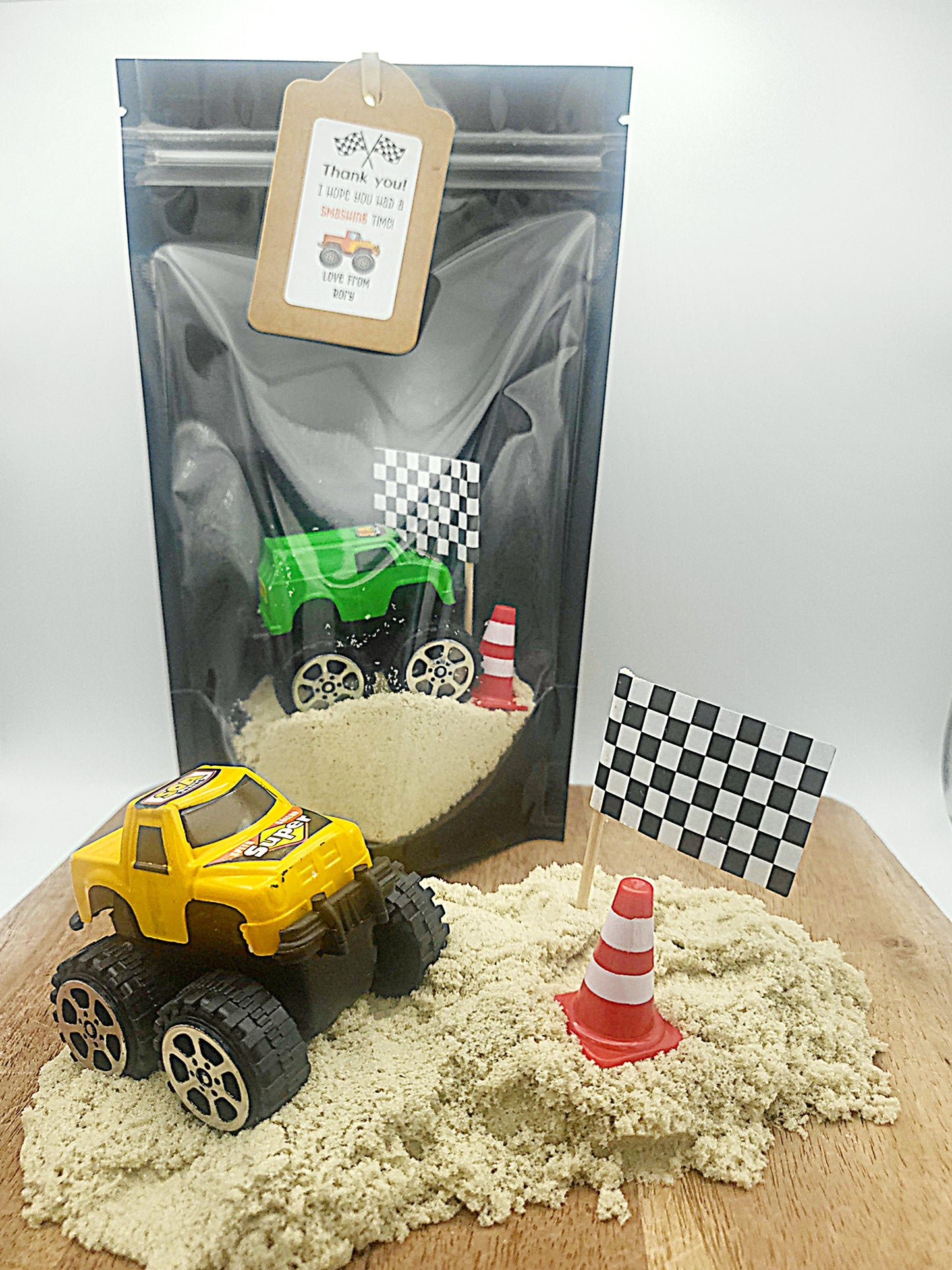 Monster truck themed party favour. Monster Truck with kinetic sand, a toy cone and wooden spade all packed in a lovely black sealable bag with a clear window to see inside