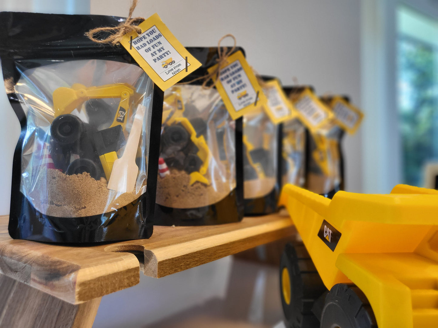 Construction Themed Party favors lined up next to a large digger vehicle. Perfect for eco eye-catching unique party favors